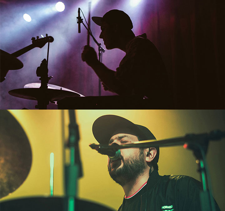 A silhouette of a person playing drums and another person singing